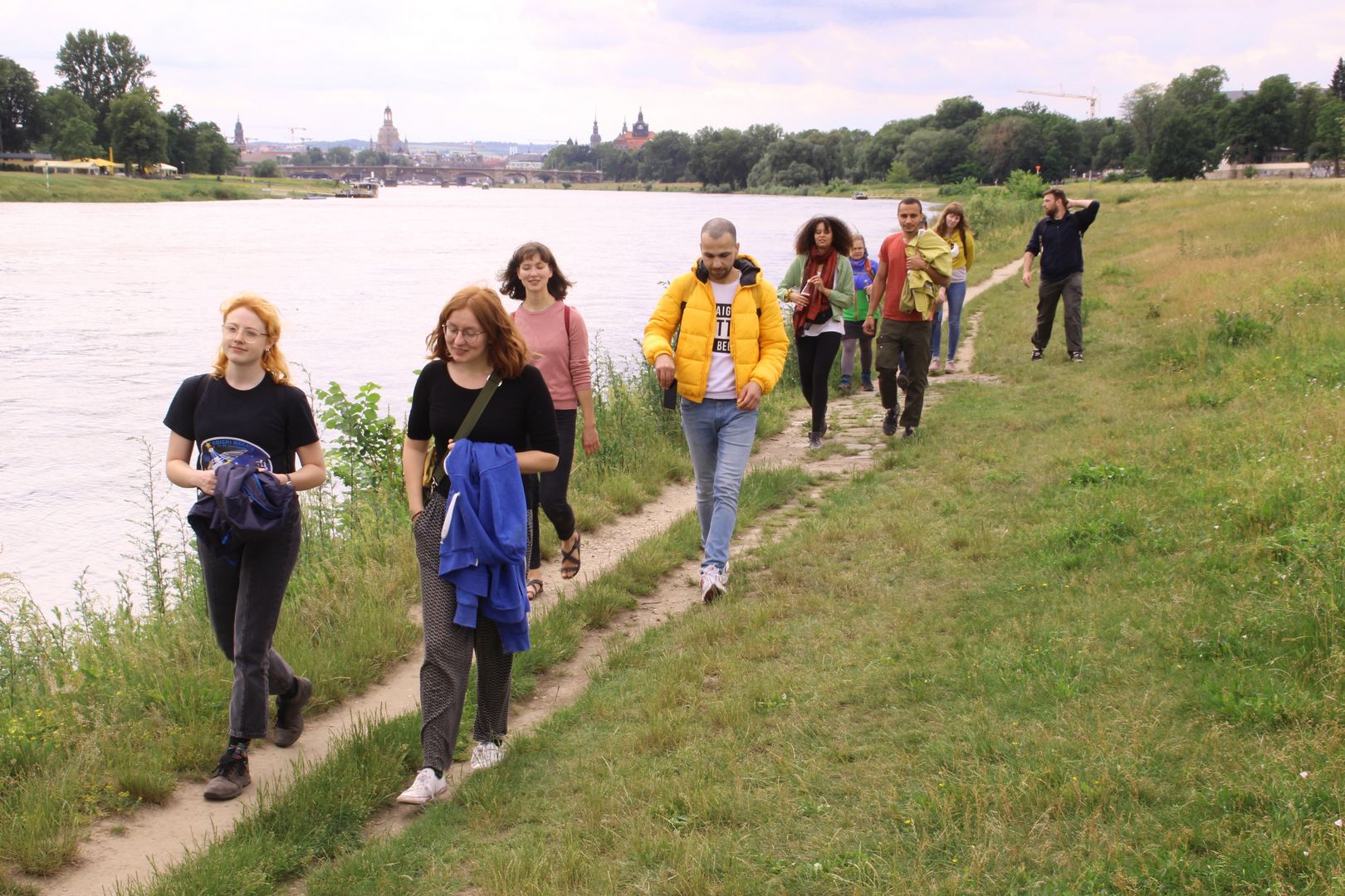 Menschen laufen in Zweierreihen am Ufer der Elbe entlang. 