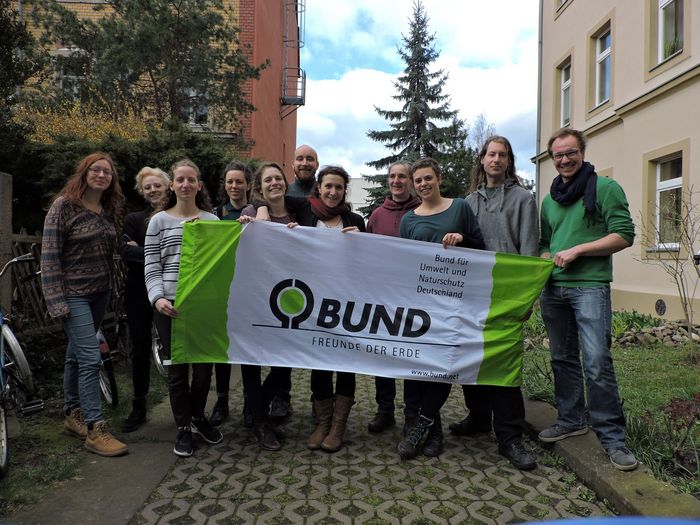 Das Büroteam des BUND Dresden im Hinterhof mit ener BUND-Flagge.