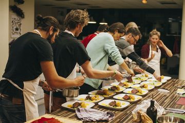 Viele Teilnehmende des Kochkurses richten das Essen auf weißen Tellern an.