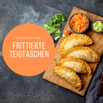 Frittierte Teigtaschen liegen mit Dip auf einem Holzbrett angerichtet.