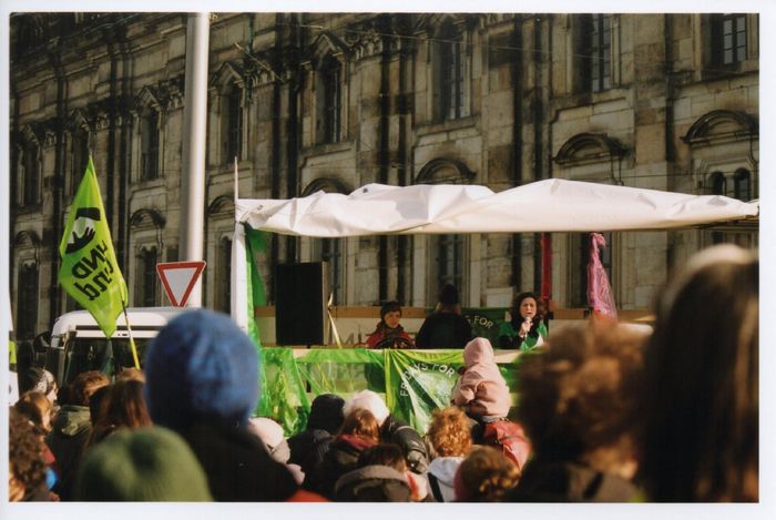 Die ehemalige Vorsitzende des BUND Dresden hält eine Rede auf einem Lauti beim Klimastreik vor einem barocken Gebäude.