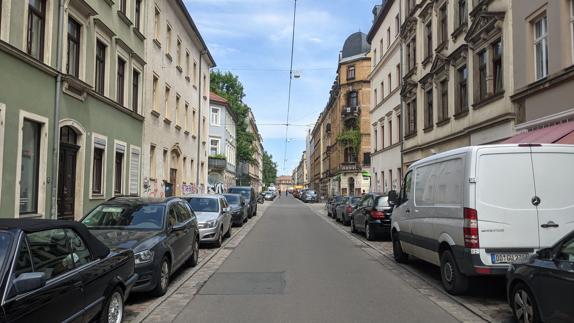 Eine städtische Straße, die links und rechts mit Autos vollgeparkt ist