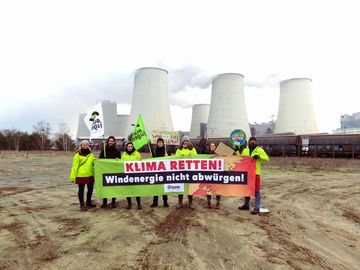 Die BUNDjugend und andere BUND-Aktive vom Landesverband Sachsen mit Fahnen und einem Banner mit der Aufschrift "Klima retten. Windenergie nicht abwürgen" vor einem Braunkohlekraftwerk.
