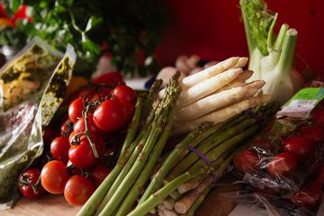 Grüner und weißer Spargel, Rispentomaten und Fenchel liegen auf einem Tisch.