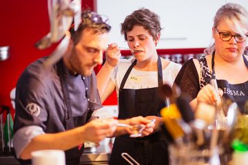 Der Koch und die Referentin Frederike Becker schmecken das Essen mit dem Löffel ab.