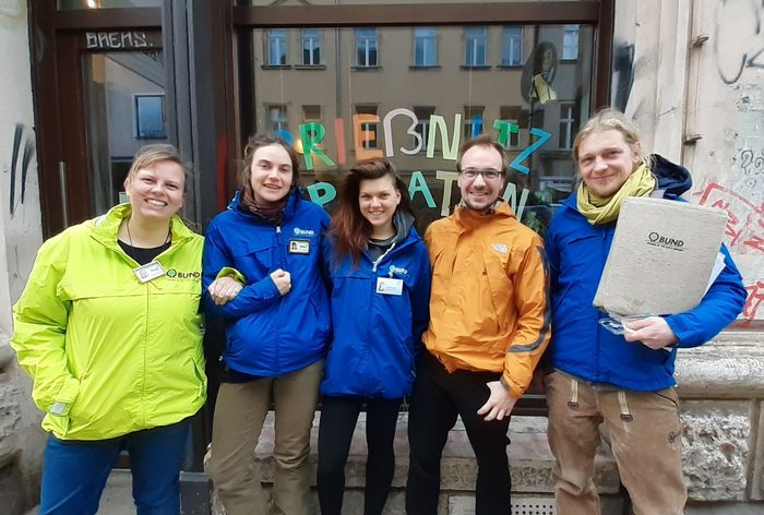Fünf Menschen stehen in Regenjacken vor dem Büro des BUND Dresden.