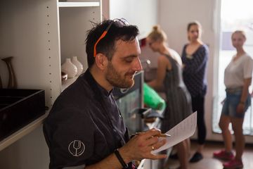 Der Profikoch liest etwas von einem handgeschriebenen Zettel ab.