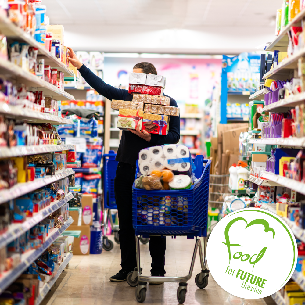 Person steht im Supermarkt und stellt Dinge aus den Regalen in einen blauen Einkaufswagen. Rechts unten das Logo von Food for Future.