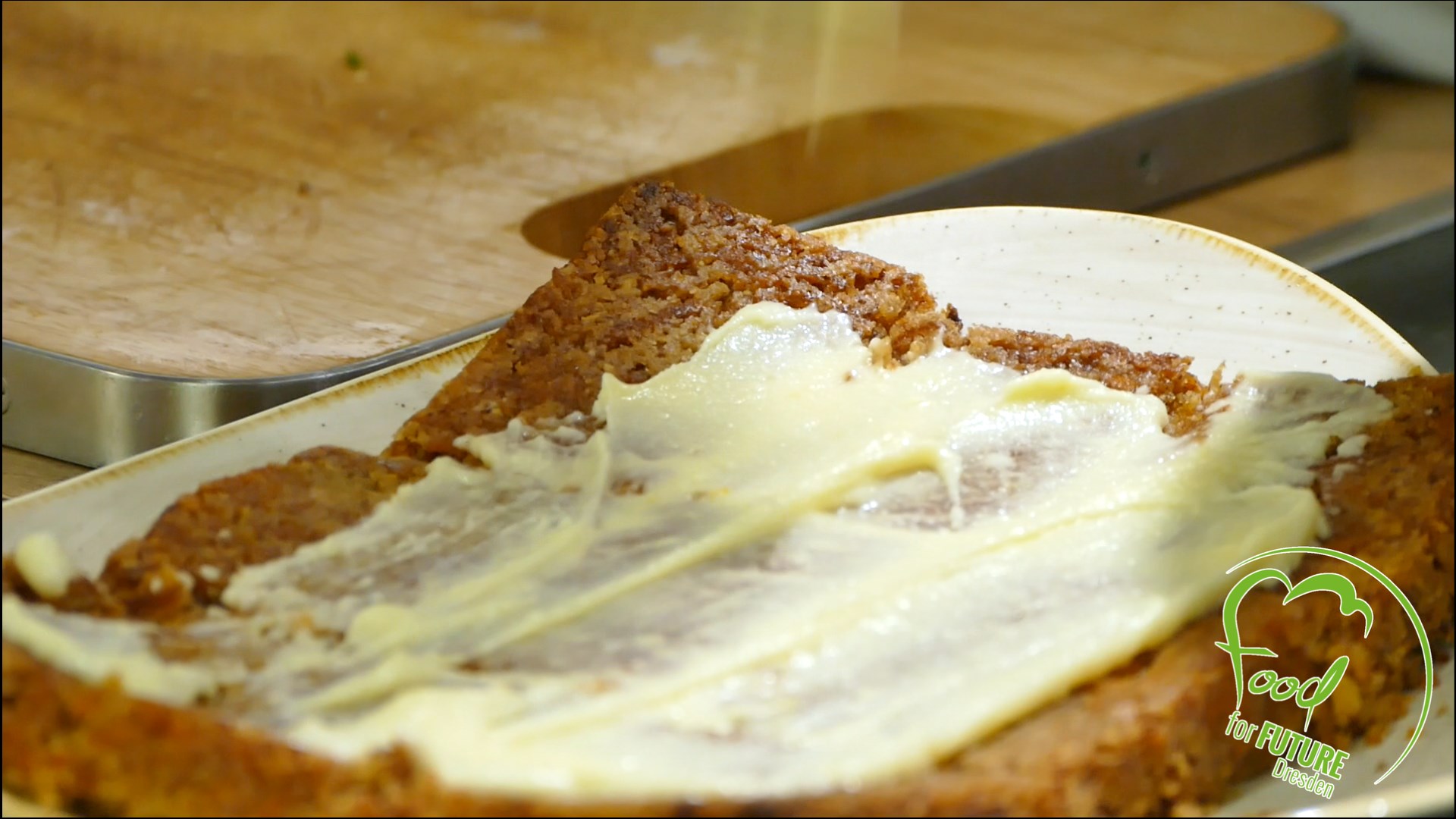 Toastscheibe, die mit Margarine bestrichen ist, liegt auf einem Holzbrett. Rechts unten das Logo von Food for Future.