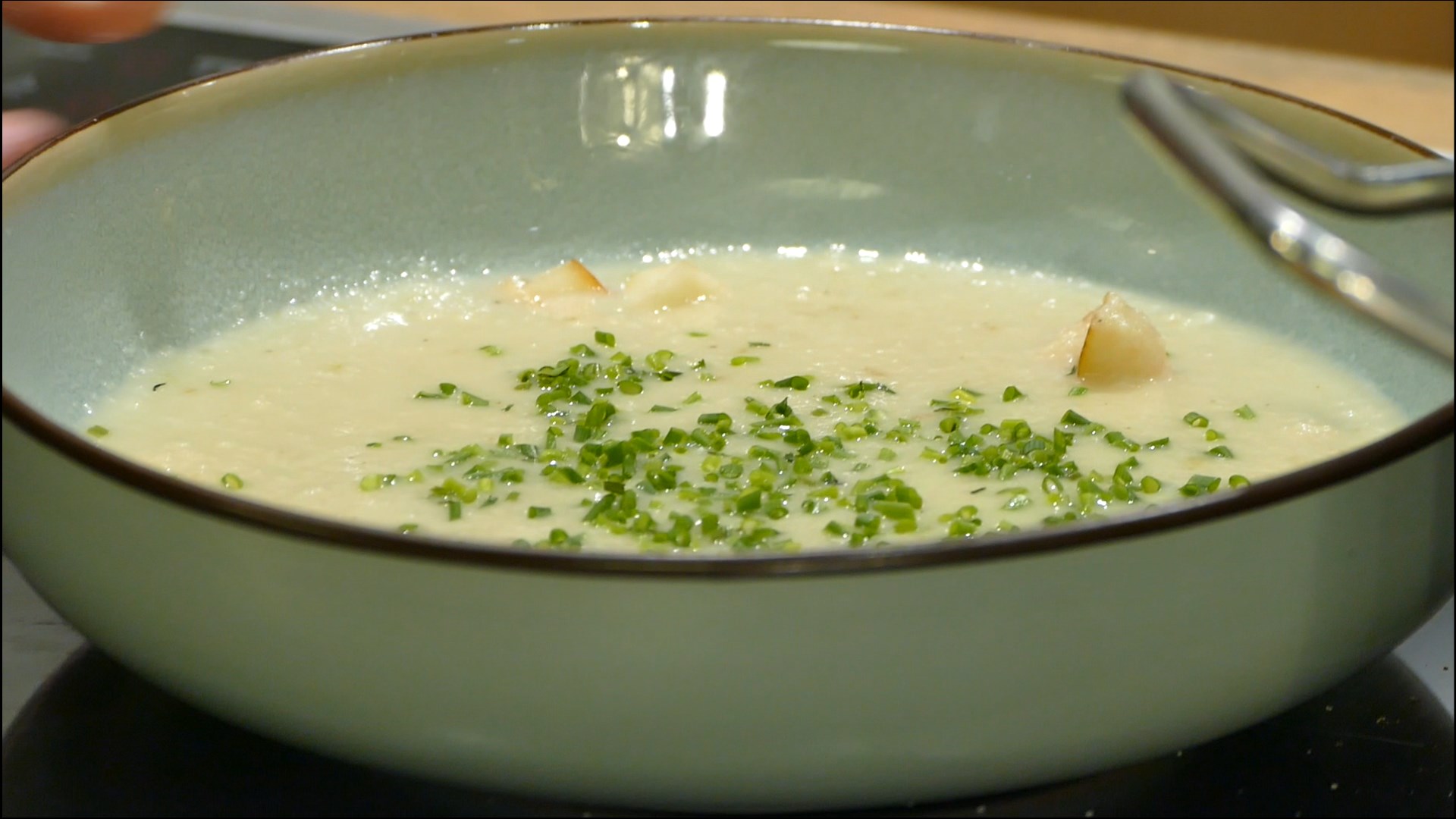 Helle Suppe in einem tiefen, blau gemusterten Teller.