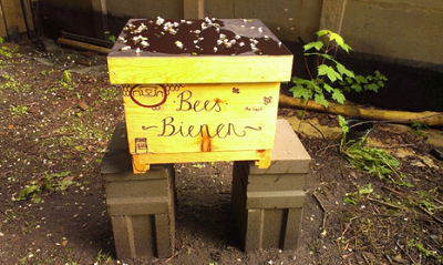 Gelber, selbstbemalter Bienenkasten.