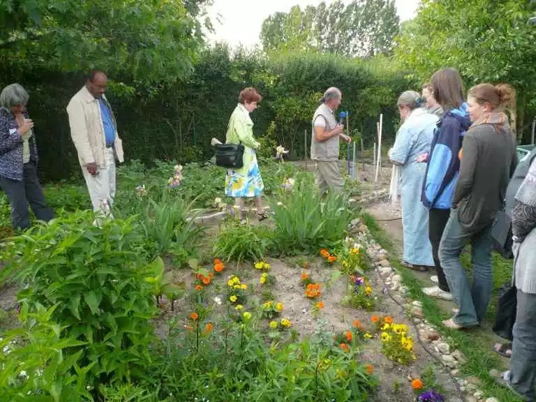 Menschen sehen sich in den internationalen Gärten um. Sie laufen zwischen unterschiedlich bepflanzten Beeten.
