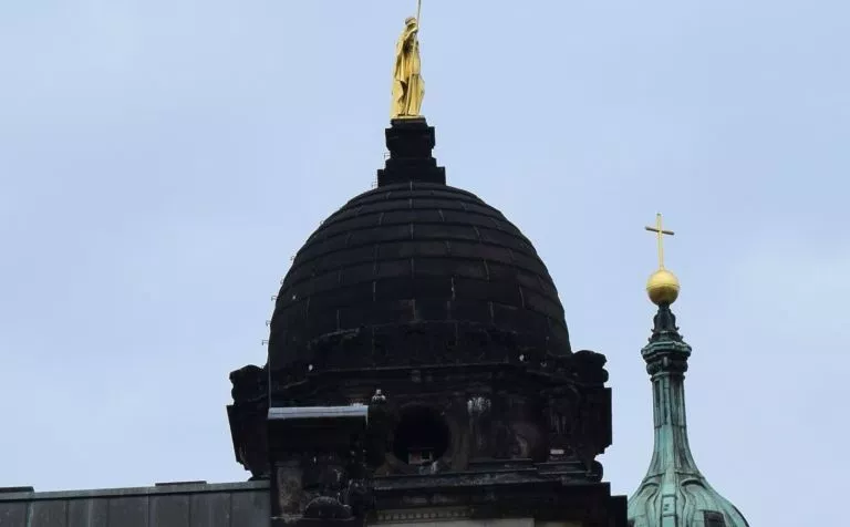 Kuppel eines barocken Gebäudes mit einer goldenen Figur auf der Spitze.