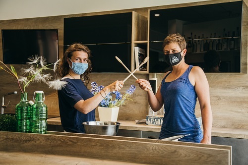 Projektreferentinnen Barbara Braun und Frederike Becker, wie sie Masken tragen und mit Kochlöffeln wie mit Schwertern kämpfen.